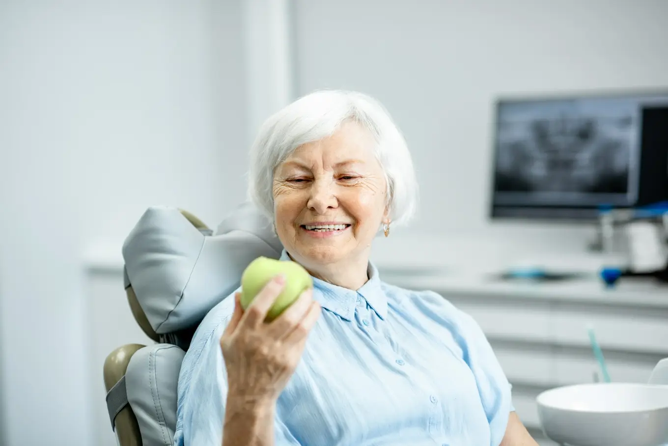 seniorka z jabłkiem na fotelu dentystycznym